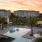 a pool with seating with buildings in the background
