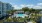 resort style pool with seating with palm trees and a building beside it